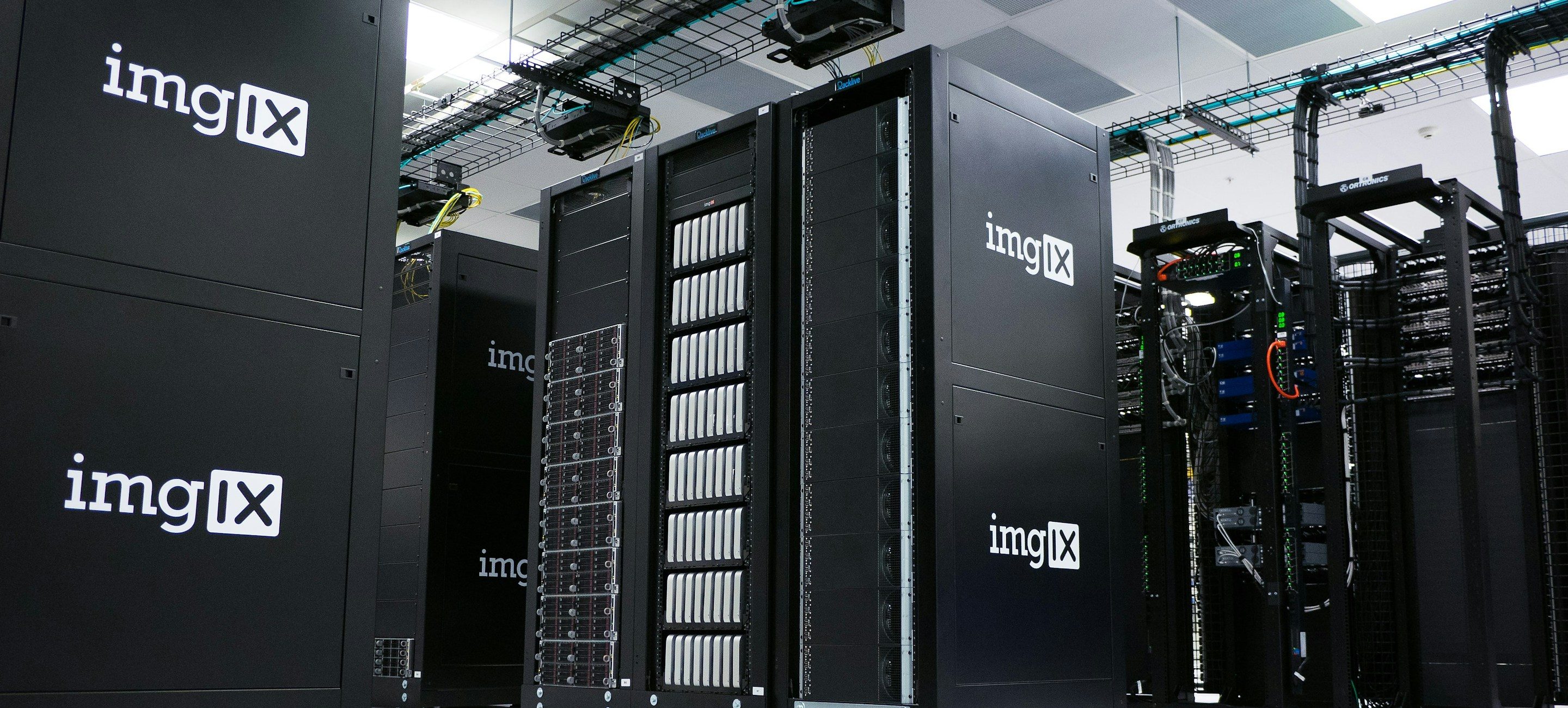 Cabinet rows on a raised floor in a production data hall, photographed down the cold aisle